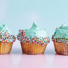 a row of cupcakes frosted with blue icing and sprinkles