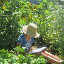 woman in sunhat sitting and drawing in garden
