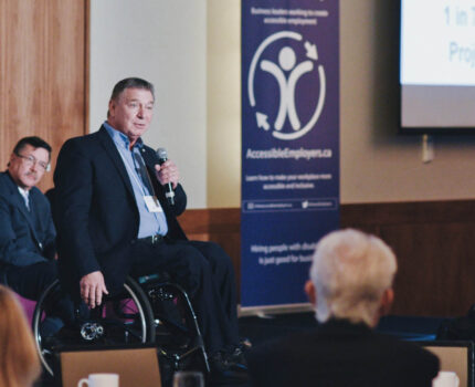 Speaker Rick Hansen in a wheelchair presenting to an audience