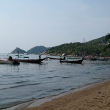 Beach with forested mountains and fishing boats