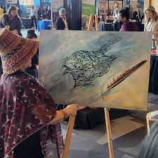 urban Indigenous artist Rosalie Dipcsu explaining her painting artwork to conference attendees