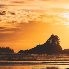 Sunset over tofino beach with small islands in the distance